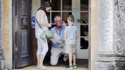 At the entrance to the house at Chartwell, a greeter is crouched down to welcome mother and son and show the spotter trail to the boy.